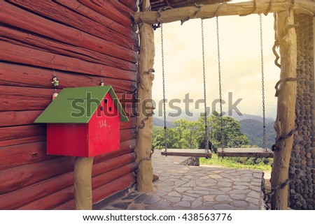 red mail box against wood wall near two swings on the hill at north of thailand