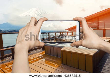 Girl taking pictures on mobile smart phone in Japanese open air hot spa onsen with view of the mountain Fuji