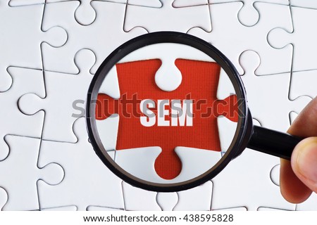 "SEM" text on red missing jigsaw puzzle with man right hand hold black magnifying glass searching for missing puzzle peace - business and finance concept