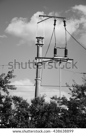 Railway electric system. Concrete pillar on a railway. Line wire over rail track. Power lines connected. 
Black and white photography. 
