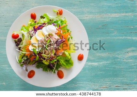 Fresh salad with fruits and greens on vintage wooden background top view with space for text. 