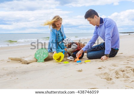 parents with son on the beach playing