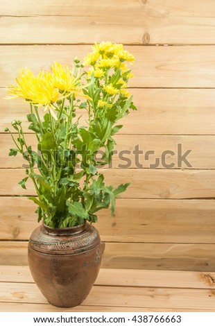 Chrysanthemum flowers in a jar on the table with wooden background
