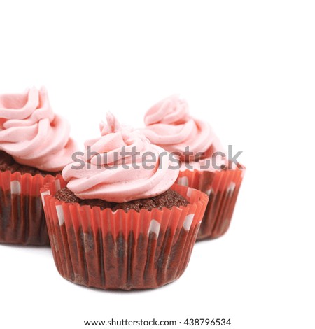 Three chocolate muffins coated with the pink cream frosting, composition isolated over the white background, close-up crop fragment