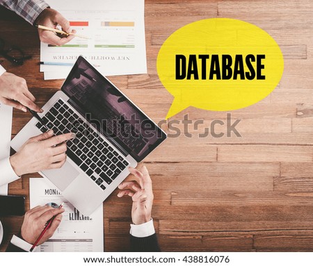 BUSINESS TEAM WORKING IN OFFICE WITH DATABASE SPEECH BUBBLE ON DESK