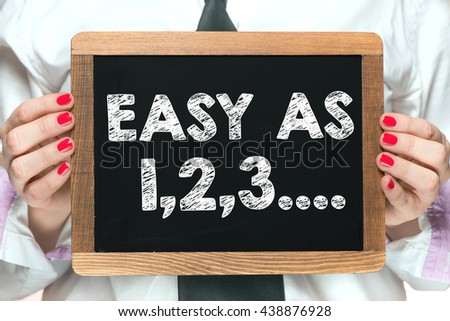 Hands with easy as 1,2,3,  inscription on blackboard. Businesswoman hands holding blackboard with handwritten easy as 1,2,3,  inscription