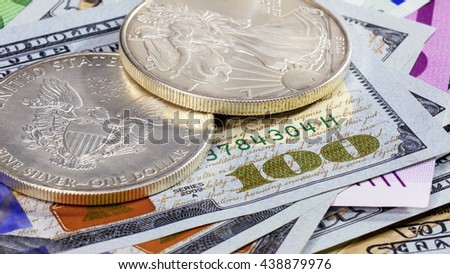 Silver American dollar coins over different bank notes background
