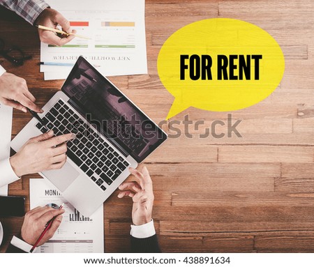 BUSINESS TEAM WORKING IN OFFICE WITH FOR RENT SPEECH BUBBLE ON DESK