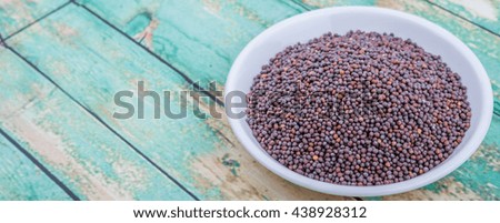 Brown Indian mustard seed in white bowl over wooden background