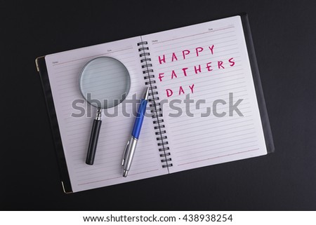 FATHERS DAY CONCEPT - A MAGNIFYING GLASS , PEN, AND A BOOK WRITTEN HAPPY FATHERS DAY WITH COPYSPACE AREA