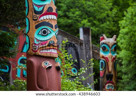 Detail of totem pole at Saxman Village tribal house near Ketchikan Alaska with Sun Raven in background Royalty-Free Stock Photo #438946603