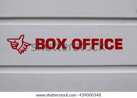 Box office sign with arrow, red typography on white wood.