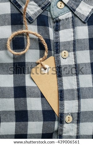 Paper price label and blue checkered shirt. Copy space.