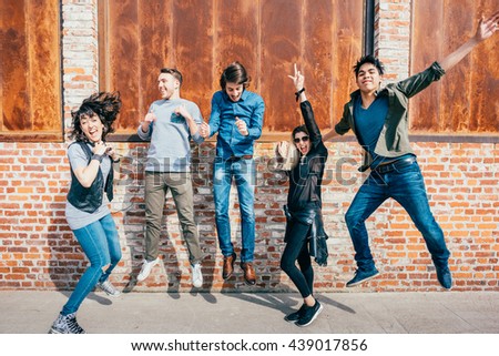 Group of young beautiful multiethnic man and woman friends having fun jumping outdoor in the city - happiness, friendship, teamwork concept  Royalty-Free Stock Photo #439017856