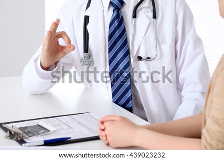 Close-up of a doctor man hands showing ok sign while consulting patient