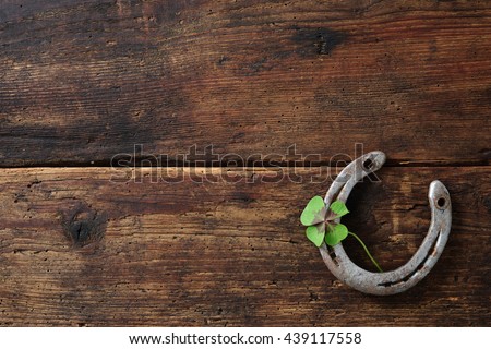 Old horse shoe with clover leaf on rustic wooden background Royalty-Free Stock Photo #439117558