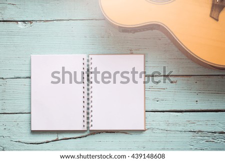 The diary blanks with an acoustic guitar on the wooden table of music composer for musical notes.