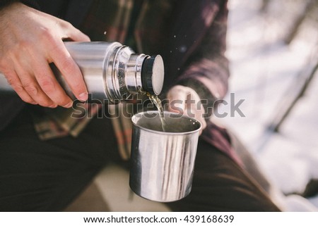 Man pours tea from a thermos. Winter forest. Close-up Royalty-Free Stock Photo #439168639