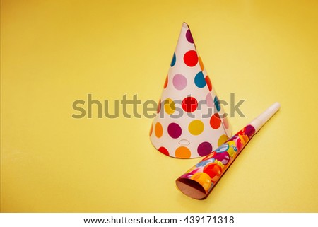 Cap and pipe for a party. On a yellow background