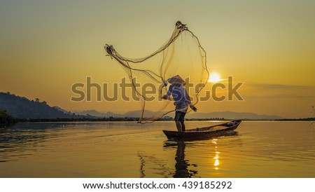 Fisherman throwing net at sunrise