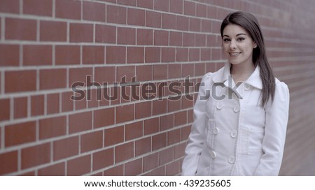 portrait of young attractive caucasian women standing next to a stone brick wall. title logo presentation background 