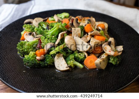 Vegan and vegetarian healthy menu; stir fry wok style mixed champignon mushroom, brocoli, carrot, mushroom tofu and crushed chillies and garlic. seasoning with soy source. Royalty-Free Stock Photo #439249714
