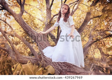 young girl in a white dress against a tree in autumn