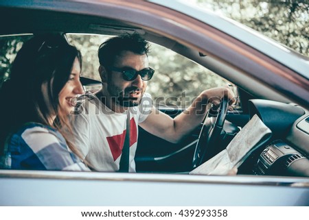 Young man and woman hold road map in a car. Travel and adventure concept. Toned picture