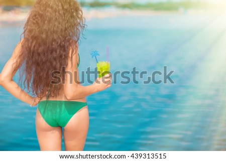 Attractive brunette on the beach. Young woman in swimwear drinking cocktail on the beach