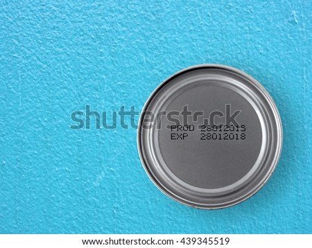 manufacturing date and expiry date printed on bottom of silver aluminum can (foods processed) on blue concrete kitchen table floor, product information for consumer, top view with copy space Royalty-Free Stock Photo #439345519