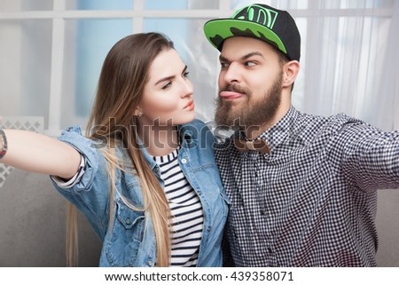 Happy cheerful couple doing  photo a phone. Hipster Boy and girl play the fool on camera      