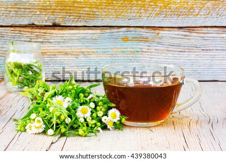 nice cup of tea with camomile flowers and camomile on an old wooden table in the cracks close up