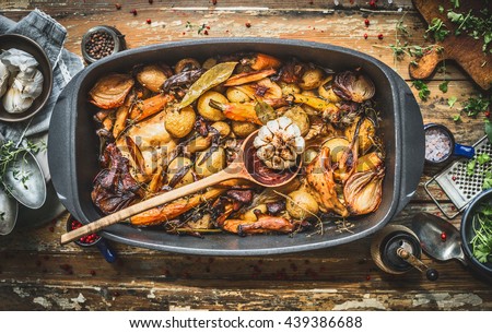  Stew with roasted vegetables, forest mushrooms and wild hunting fowl in cooking pot with wooden spoon. Rabbit ragout on rustic aged background with spoons,plates and fresh seasoning, top view Royalty-Free Stock Photo #439386688