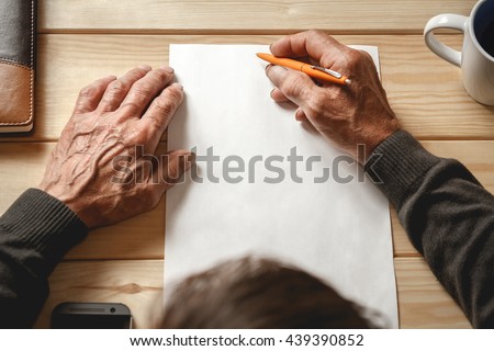 The old man wrote a testament, sitting at a wooden table Royalty-Free Stock Photo #439390852