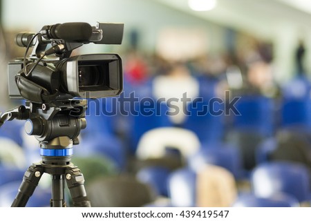 Front View of Professional Videocamera. Positioned Against Blurred Background. Horizontal Image