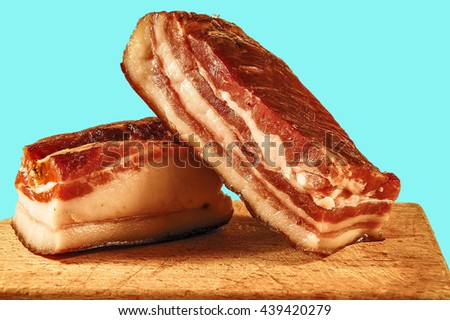 Two pieces of meaty smoked bacon home on a kitchen cutting board.                        