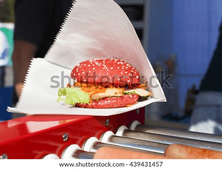 Fresh red bun burger. Cookout american bbq food. Big burger with grilled barbecue steak meat, korean carrot and lettuce closeup in wrapping paper. Street food, fast food. Creative, unusual hamburger