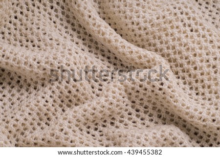 Knitted beige wool fabric into the net with gold thread. Textures, background