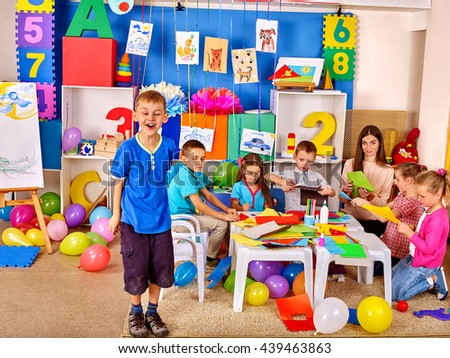 Children with teacher working with colored paper on table in kindergarten .Creative development of children.