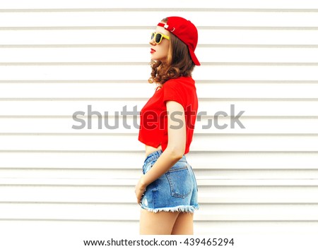 Fashion pretty woman in sunglasses and shorts looks away over white background