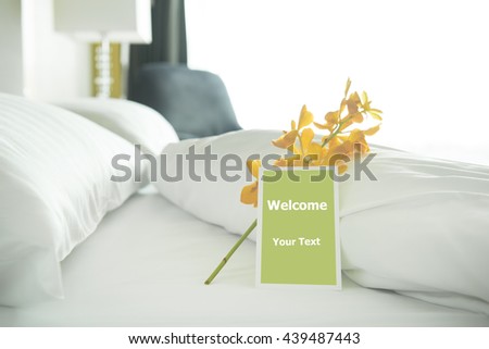 Welcome card placed inside a hotel room bed with Yellow orchid.
