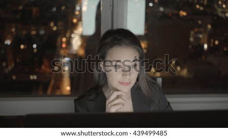 confident businesswomen sitting in front of computer screen working in modern office at night 