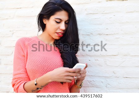 Young beautiful latin woman texting on her phone. Woman using a cellphone wearing casual clothes.