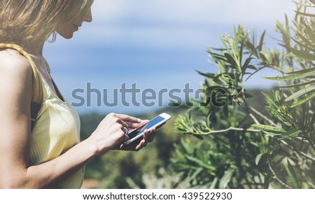 Hipster young girl with bright backpack looking at phone. Said view tourist traveler on background green mountain, blue sea. Mock up for text message. Female hands using smartphone, holding gadget