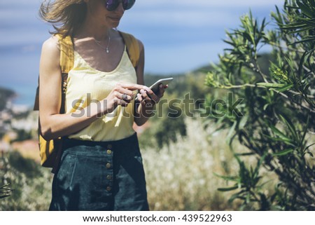 Hipster young girl with bright backpack looking phone. Said view tourist traveler on background mountain, blue sea. Mock up for text message. Female hands using smartphone, holding modern gadget