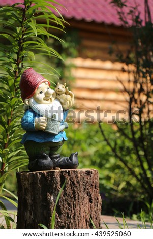 Little garden gnome figurine standing on a tree stump in the backyard