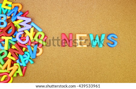 The colorful word "NEWS" next to a pile of other letters over the brown board surface composition.