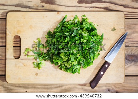 Chopped spinach, lettuce, parsley on a cutting Board with a knife. Top view Royalty-Free Stock Photo #439540732