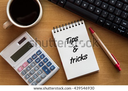 Tips & tricks- handwriting on a notebook with cup of coffee, calculator, keyboard.