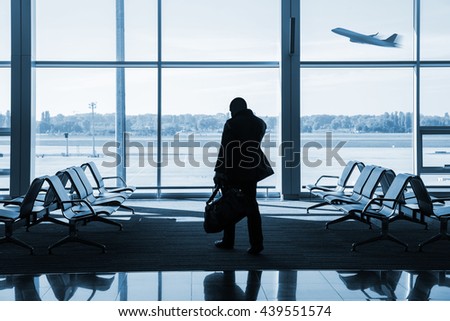 silhouette of passenger waiting for the flight inside airport terminal lounge, blue toned